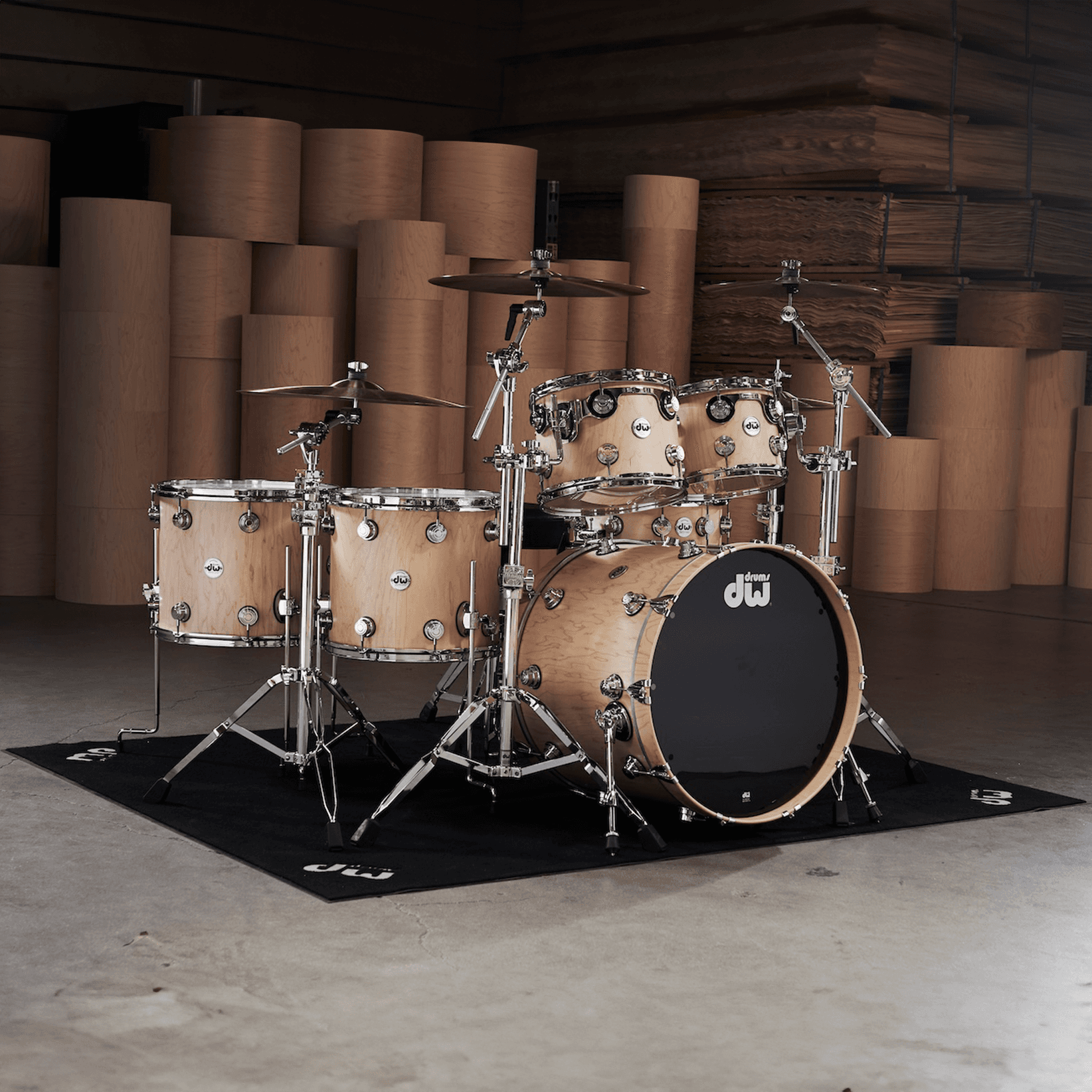 DW maple kit sitting on top of a black DW Drum rug.